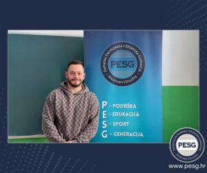 Man in a gray patterned hoodie stands beside a blue PESG banner with the logo and the words Podrška, Edukacija, Sport, Generacija; chalkboard on the left and a PESG logo at the bottom right corner.