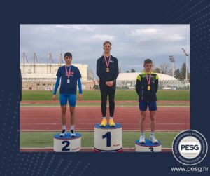 Three young athletes stand on a medals podium (gold center, silver left, bronze right) at a track field, stadium in background, PESG logo visible in corner.