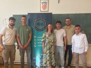 Six students posing indoors beside a blue PESG banner in a classroom.